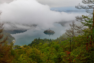 Aerial view of Island in Bled Lake, with Bled city in background. Church and other buildings in the...