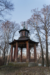 gazebo with concrete columns in Chinese style with stained glass windows in the park in early spring