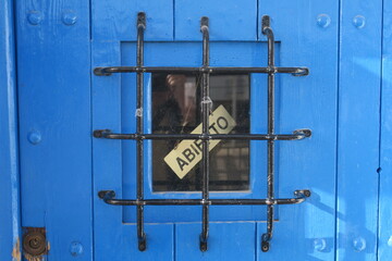 Abierto (Ouvert) Inscription en espagnol sur une porte derrière une grille en fer. 
