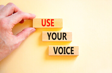 Use your voice symbol. Concept words Use your voice on wooden blocks on a beautiful white table white background. Businessman hand. Business and use your voice concept. Copy space.