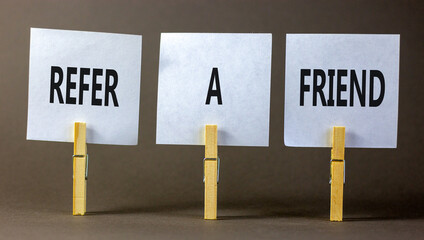Refer a friend symbol. Concept words Refer a friend on white paper on a beautiful grey table grey background. Business and refer a friend concept. Copy space.