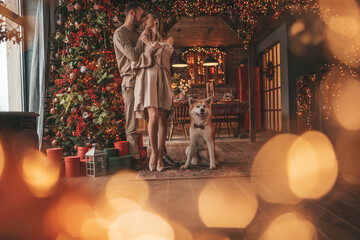 Candid authentic happy married couple spends time together with japanese dog at Xmas lodge