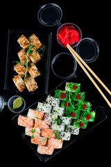 Obraz na płótnie Canvas Sushi rolls with tuna, salmon, shrimp, cucumber, avocado, cream cheese, seaweed, red flying fish caviar, sesame, wasabi, ginger, soy sauce and chopsticks.