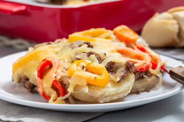 Casserole with potatoes, sausage and colorful bell pepper, on plate, horizontal, closeup