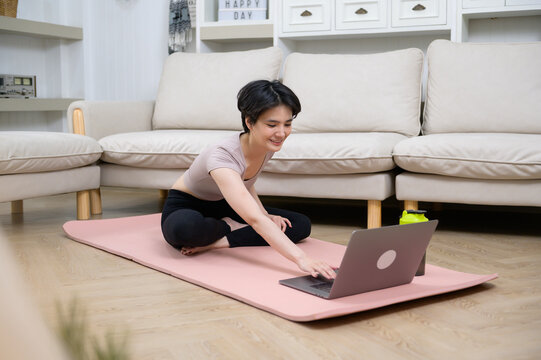An Asian young woman is workout on fitness mat , exercise at home , healthy lifestyle concept