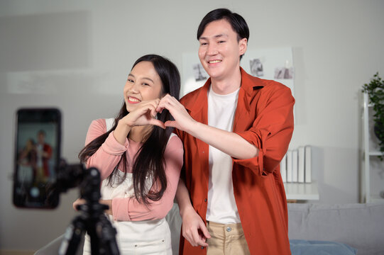 Asian young couple tiktokers are making video dancing  via smartphone together,  share video content on social media.