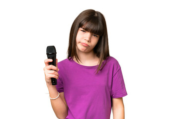 Little singer girl picking up a microphone over isolated background with sad expression