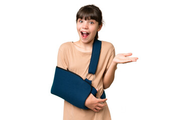 Little caucasian girl with broken arm and wearing a sling over isolated background with shocked...
