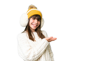 Little caucasian girl wearing winter muffs over isolated background presenting an idea while...