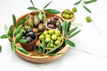 olives berries in wood bowls and oil in glass bottles on a light background. Healthy and detox food concept