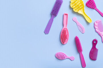 Hair care is a creative concept. Colored doll combs on a blue background. Copy space