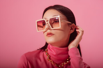Beautiful fashionable woman wearing trendy pink big square sunglasses, chunky chain, stylish...