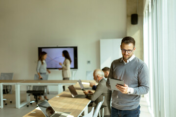 Young modern businessman using digital tablet in the office