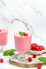Yogurt smoothie with raspberries in glass on white marble table. weight loss concept. vertical image. place for text