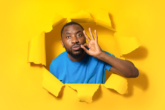 My lips are sealed with promise. Serious african american man keep mouth shut, making zip gesture, staying silent