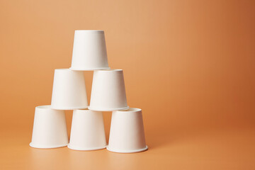 Pyramid stack of disposable white recyclable cardboard paper cups standing on each other isolated...