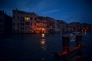 Venice deep evening night landscape with the view of venetian houses with luminous windows the view accross the Grand canal with bitts in the foreground