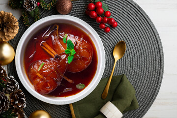 Pears cooked with red wine and cinnamon on a table with Christmas decorations. Christmas Dessert.