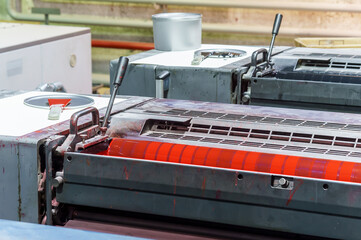 Section of the printing press. Red magenta ink in the printing press.