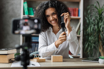 African american woman doing live stream while unpacking box with new smart watch. Female blogger sharing her feedback about modern gadget with her subscribers.