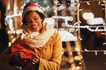 Black Woman With Sparklers And Red Gift During Xmas Holidays In The City
