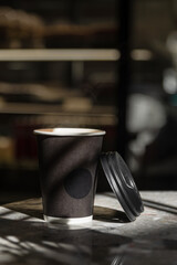 Closeup of blank craft paper coffee cup on the wood table. Space for you advertising. mockup