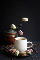 A cup of hot coffee with milk and delicious pasta cakes, small marshmallows.
