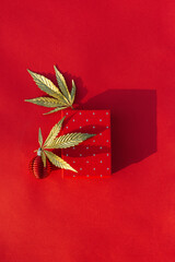 Fototapeta premium Christmas background with gift box, golden leaf marijuana red festive background