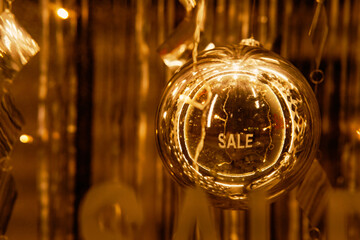 Golden Christmas ball with the word SALE in the shop window