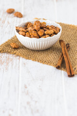 Bowl of sweet candied almonds on white rustic wooden background