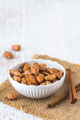 Bowl of sweet candied almonds on white rustic wooden background