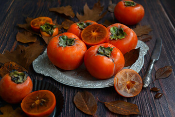 Ripe orange persimmon fruits. fresh persimmon on a metal dish on a wooden table
