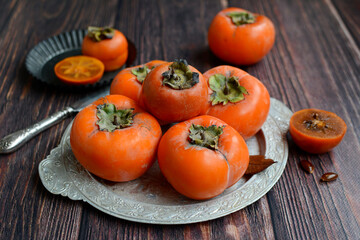 Sweet juicy persimmon fruits on a rustic background. Autumn, harvest