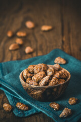 Bowl of sweet candied almonds on rustic wooden background