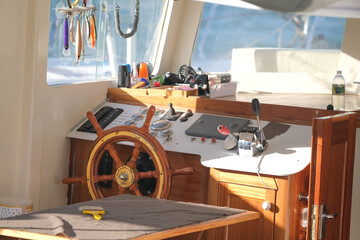 Wooden steering wheel and dashboard inside the yacht