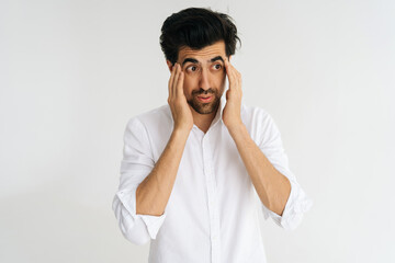 Studio portrait of unhappy Caucasian young man massaging temples suffering from headache painful,...