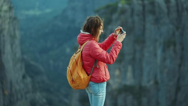 girl hiker takes pictures or video of stunning Tazi canyon landscape on her smartphone. Happy woman on top of cliff enjoying mountain view, hike in famous touristic place in Turkey.
