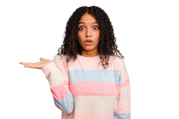 Young Brazilian curly hair cute woman isolated impressed holding copy space on palm.