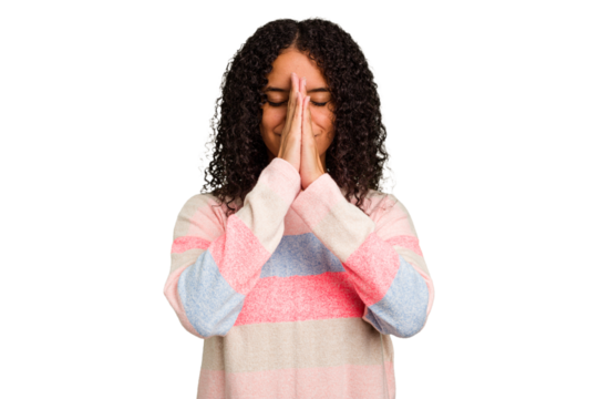 Young Brazilian curly hair cute woman isolated holding hands in pray near mouth, feels confident. - Powered by Adobe