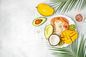 tropical bowl with avocado, prawns, rice, mango, kiwi and coconut, tropical food on the sea beach, Organic and healthy food, place for text, top view