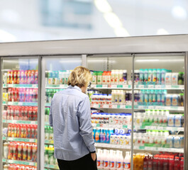  Man choosing frozen food from a supermarket freezer., reading product information