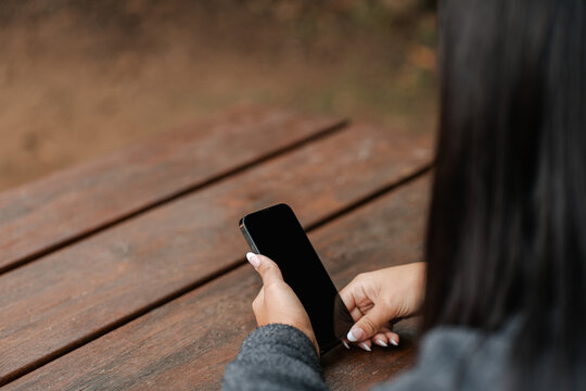 Crop woman using smartphone in park