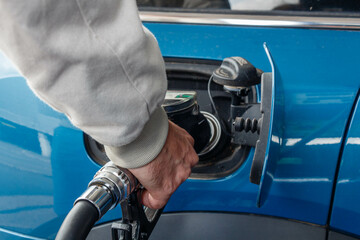 Close up of man hand refueling a blue car at a petrol station. Oil price crisis