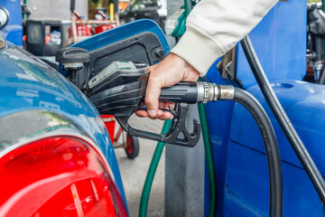 Close up of man hand refueling a blue car at a petrol station. Oil price crisis