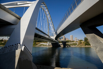 Obraz premium Modern arc bridge over the river, day traffic, bike road, summer time. modern architecture, panorama of the city Edmonton