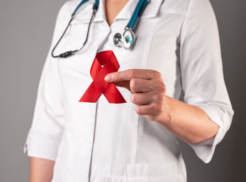 Red satin loop ribbon in doctors hand, symbol of HIV and AIDS day. 1 December support and care. High quality photo