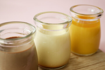  Caramel, chocolate and mango pudding in a glass jar on pink background 