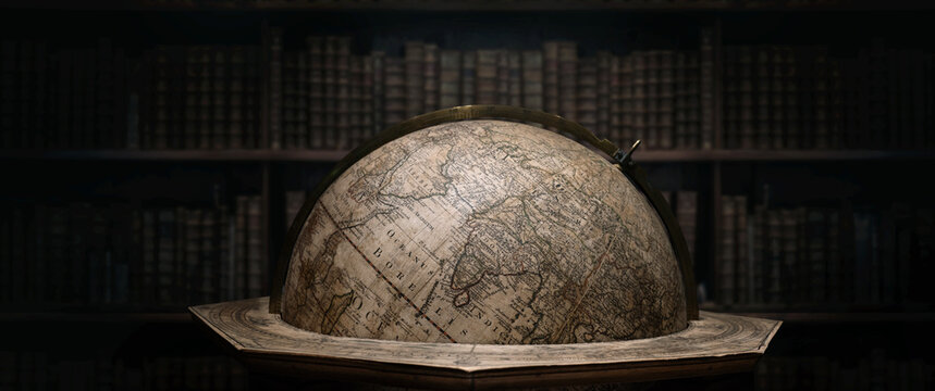 Old geographical globe in cabinet with bookselfs. Science, education, travel, vintage background. History and geography team. Ancience, antique globe on the background of books.