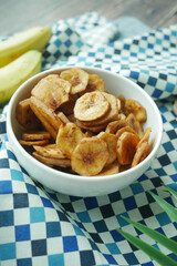 Close up of dried banana chips in a bowl on table .