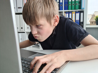 Surprised teenage boy excitedly looks at laptop screen